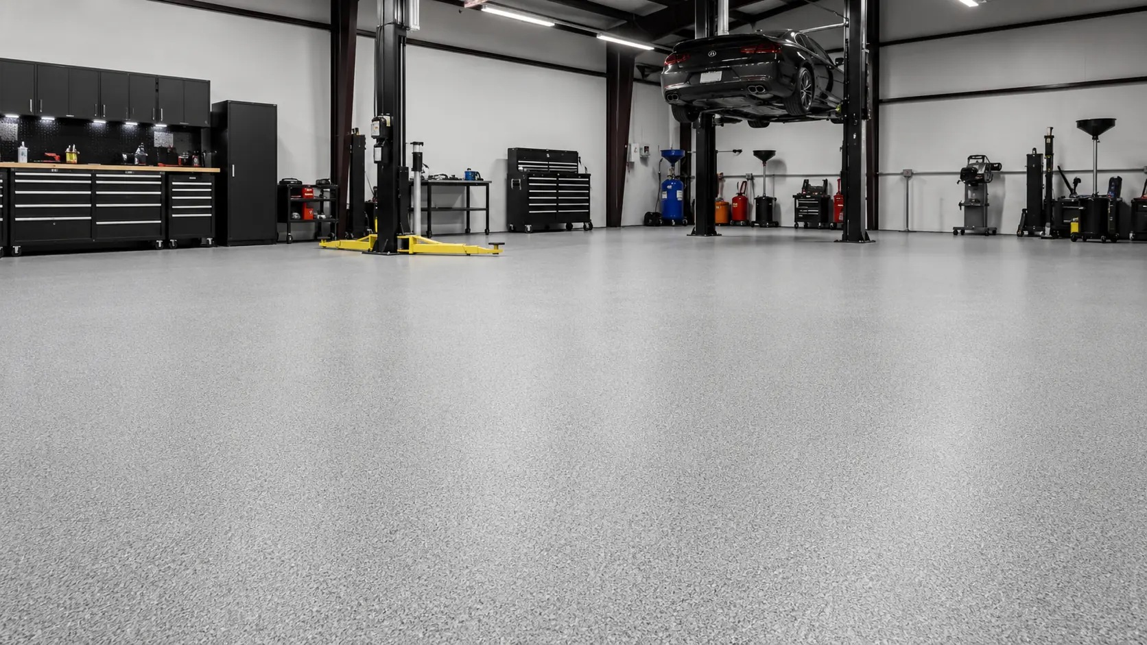 Clean automotive workshop with a matte grey resin floor, illustrating the finished surface achievable after concrete preparation in Melbourne.