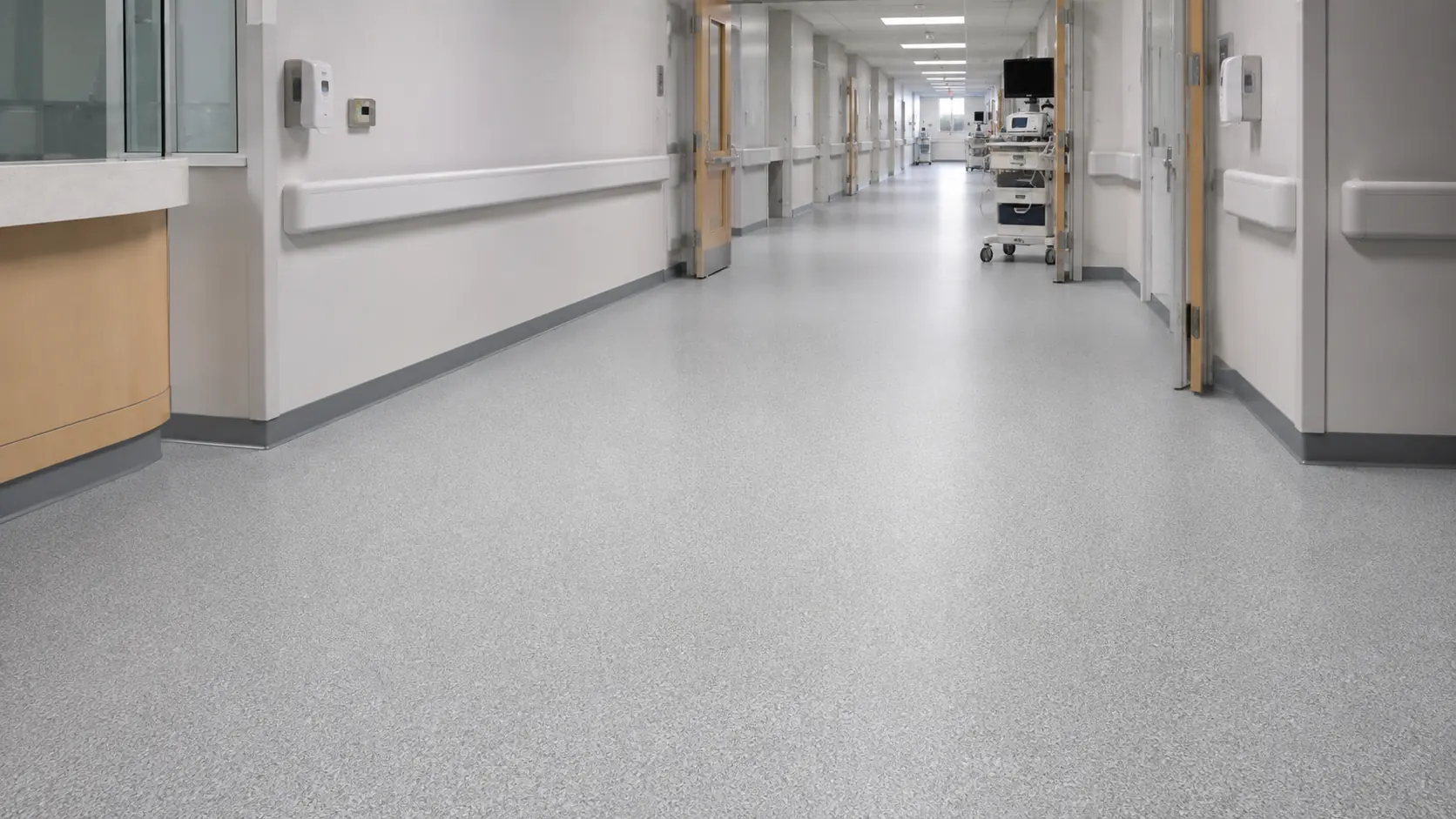 Healthcare corridor with a seamless matte light grey hygienic resin floor, illustrating institutional flooring available in Melbourne.